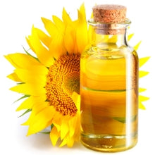 A sunflower head with a glass bottle of sunflower seed oil in front of it