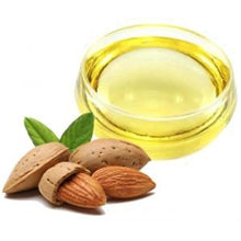 Cut almond nuts in front of a small dish of sweet almond oil 